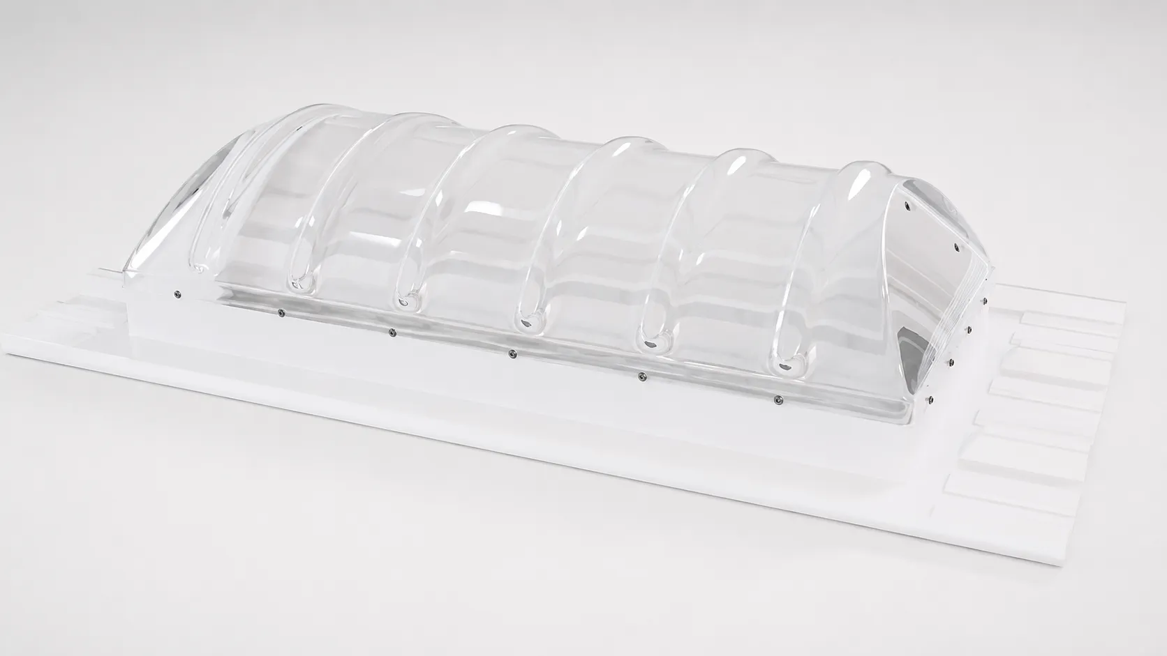 Clear thermoformed polycarbonate barrel-vault rooflight mounted on a white base plate
